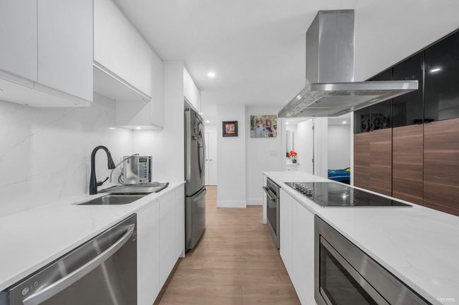 Kitchen with white cabinetry, a sink, stainless steel appliances, exhaust hood, and modern cabinets | Image 20
