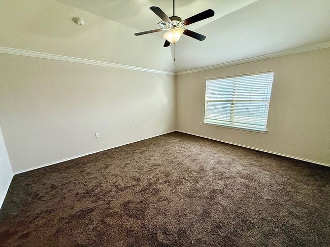 Spare room featuring lofted ceiling, dark colored carpet, a ceiling fan, a smoke detector, and ornamental molding | Image 10