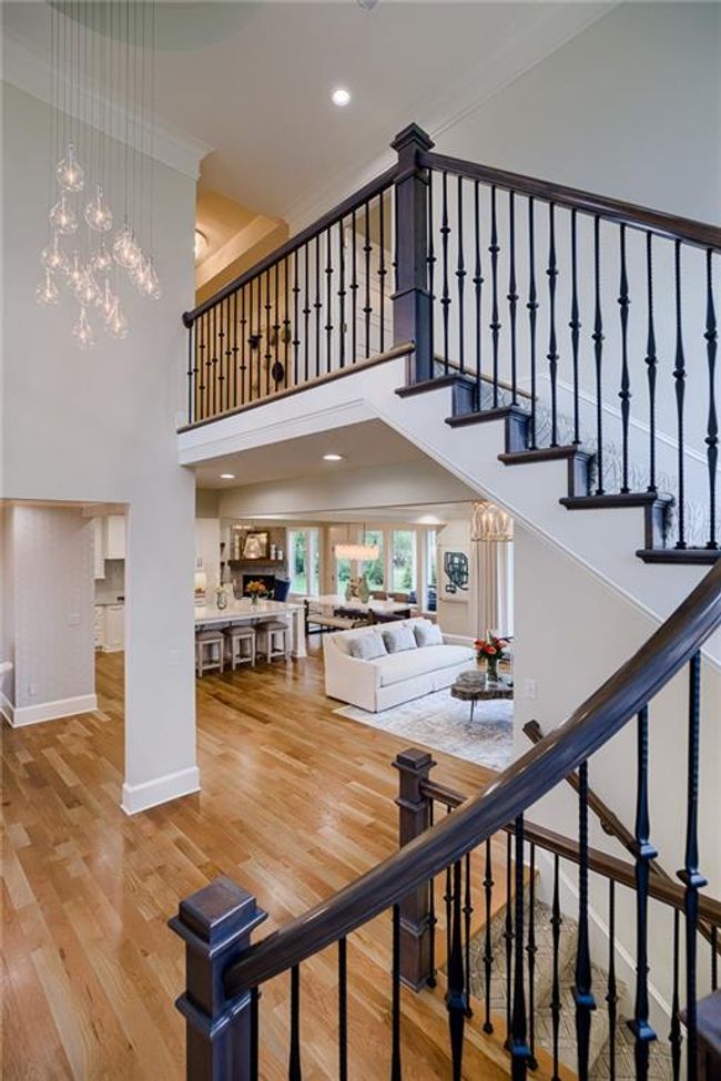 Staircase featuring a towering ceiling, an inviting chandelier, light wood-type flooring, and crown molding | Image 25