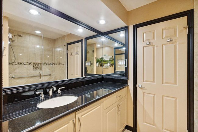 Sleek secondary bathroom featuring granite countertops. | Image 21