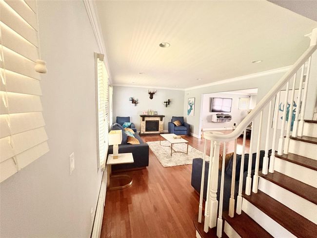 Living room featuring crown molding, baseboards, recessed lighting, wood finished floors, and stairs | Image 6