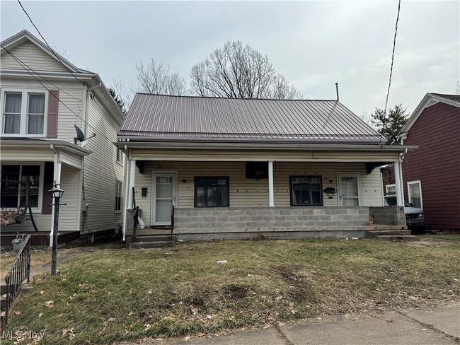 View of front of home with metal roof, a porch, and a front yard | Image 5