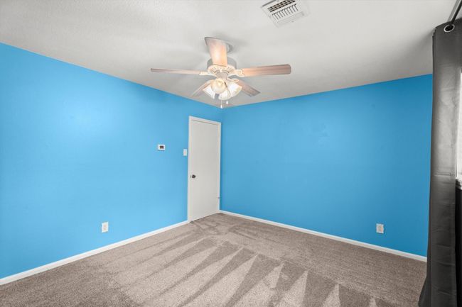 This room features bright blue accent walls, neutral carpeting, and a large window providing lots of natural light. | Image 32