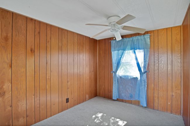 Carpeted spare room featuring ceiling fan and wood walls | Image 13