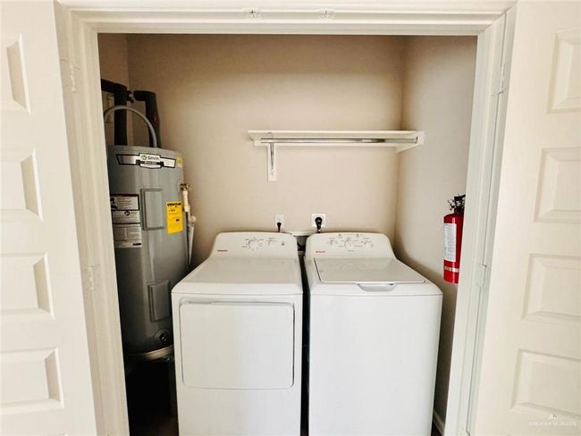Laundry area featuring washing machine and dryer and water heater | Image 23
