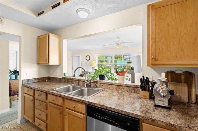 Kitchen with a textured ceiling, dishwasher, a ceiling fan, a sink, and light tile patterned floors | Image 4