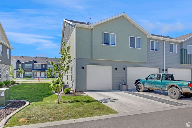 View of front facade featuring driveway, an attached garage, a front lawn, a residential view, and cooling unit | Image 21