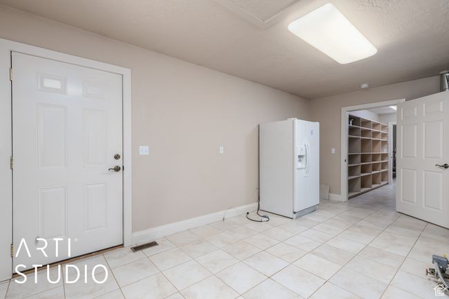 Empty room with light tile patterned floors, baseboards, and visible vents | Image 24