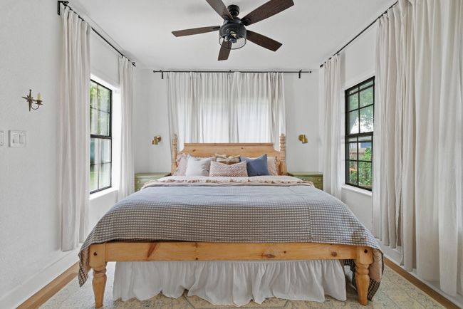 primary Bedroom on the first floor featuring multiple windows, a ceiling fan, and wood finished​​‌​​​​‌​​‌‌​‌‌​​​‌‌​​‌‌​‌​​​​​‌ floors | Image 12