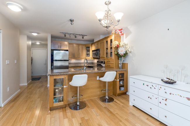 Kitchen with a sink, brown cabinets, glass insert cabinets, stainless steel appliances, and a peninsula | Image 10