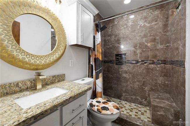 Bathroom with vanity, toilet, and a shower with shower curtain | Image 7