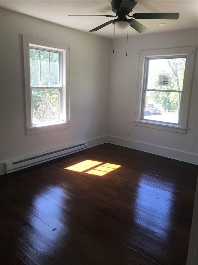 Empty room featuring baseboard heating, ceiling fan, a wealth of natural light, and dark hardwood / wood-style floors | Image 26