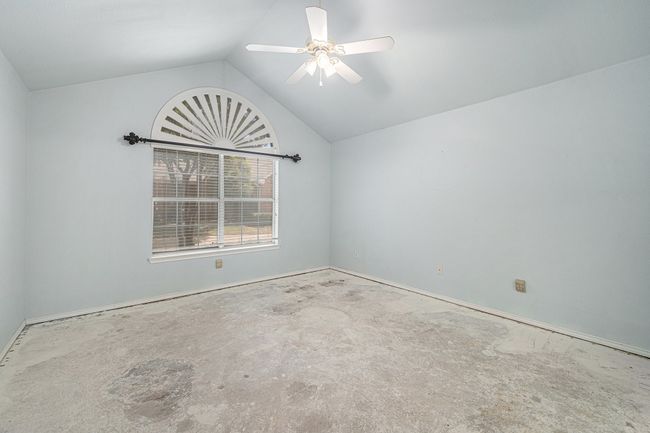 Primary Bedroom with ceiling fan and vaulted ceiling. The carpet has been removed and you can see the concrete flooring. | Image 9