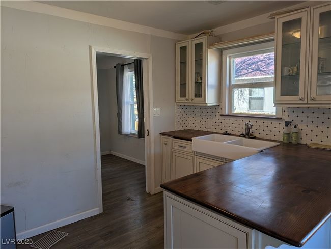 Kitchen with tasteful backsplash, dark wood-style flooring, a sink, and wooden counters | Image 7