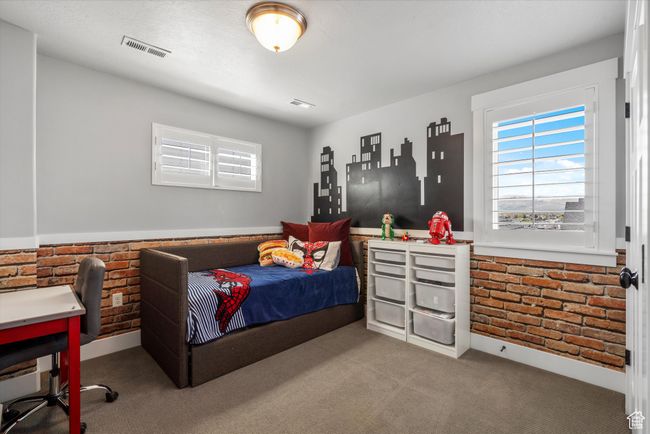 Carpeted bedroom with visible vents, multiple windows, and brick wall | Image 36