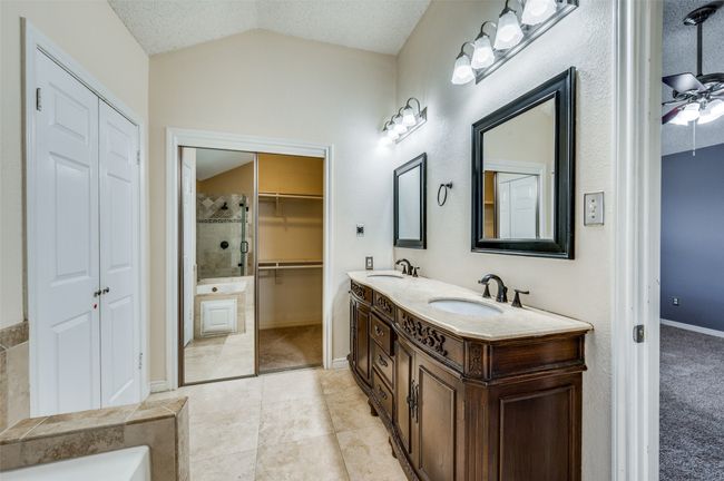 Bathroom featuring vaulted ceiling, double vanity, a walk in closet, and tile patterned floors | Image 14
