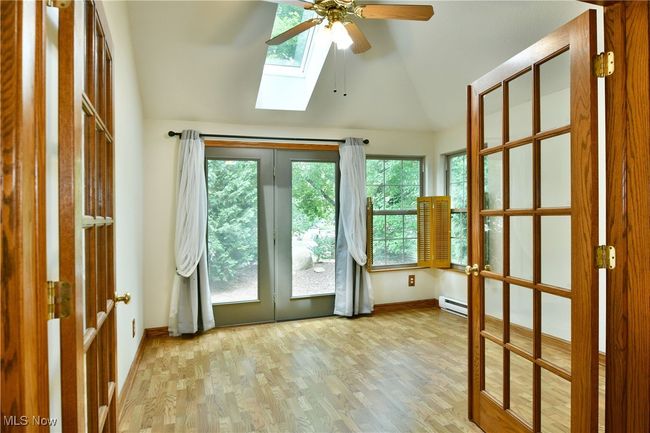 Doorway featuring lofted ceiling, a baseboard radiator, a skylight, a ceiling fan, and wood finished floors | Image 14