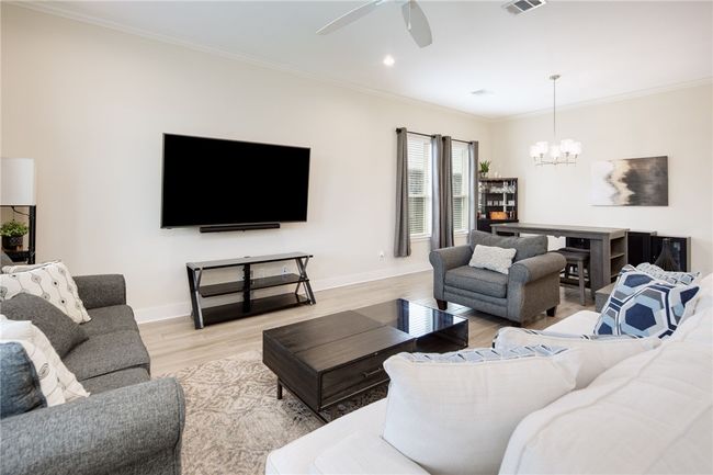 Living room with a chandelier, light wood-type flooring, baseboards, ornamental molding, and ceiling fan | Image 5