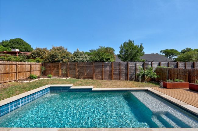 View of swimming pool featuring a fenced in pool, a fenced backyard, and a wooden deck | Image 26