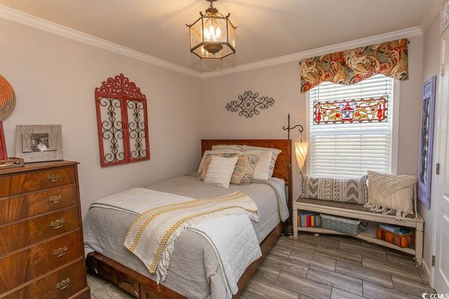 Bedroom featuring wood finished floors, a textured ceiling, and crown molding | Image 23