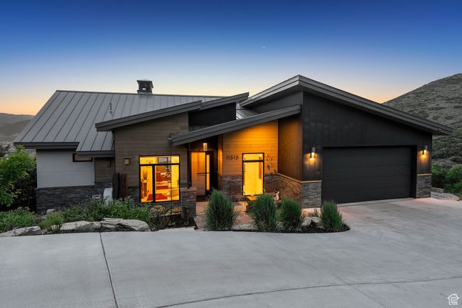 Contemporary home featuring a standing seam roof, stone siding, a garage, driveway, and a metal roof | Image 96