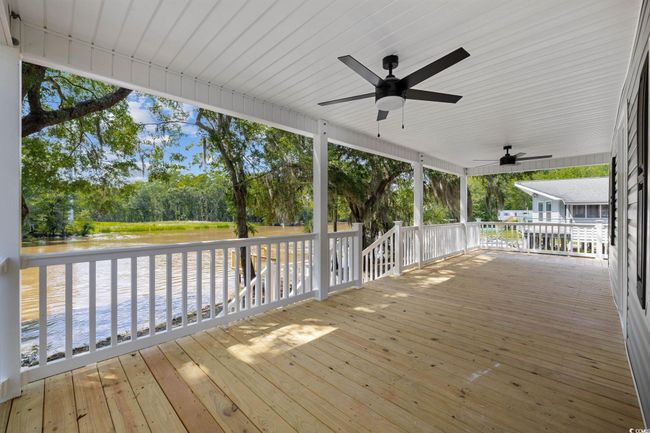 Wooden deck featuring ceiling fan, a water view, and view of wooded area | Image 28
