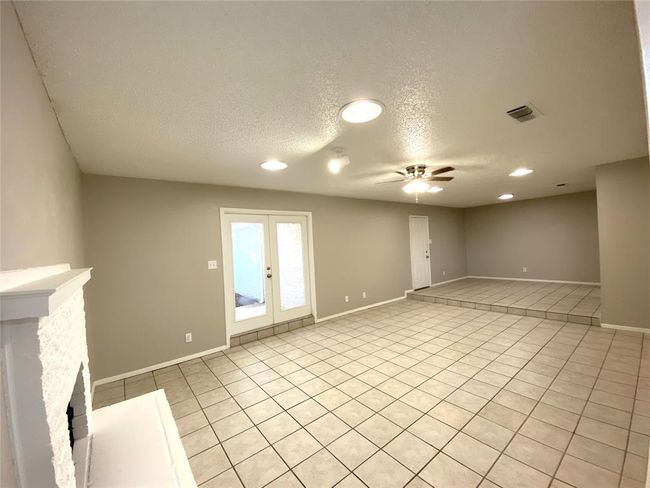 8836 Living room with ceiling fan, light tile flooring, a fireplace, and a textured ceiling | Image 12