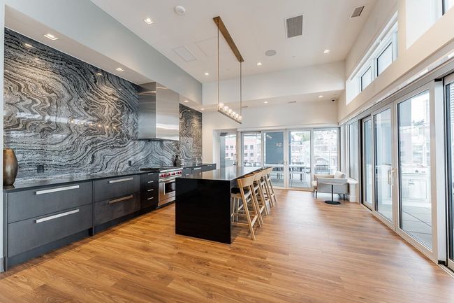 Kitchen with high end stainless steel range, modern cabinets, wall chimney exhaust hood, visible vents, and a center island | Image 24
