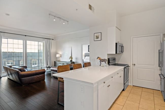 Kitchen with a peninsula, a breakfast bar, open floor plan, white cabinets, and stainless steel appliances | Image 7