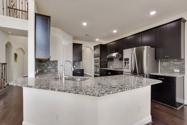 Kitchen with arched walkways, appliances with stainless steel finishes, a peninsula, dark wood-type flooring, and recessed lighting | Image 13