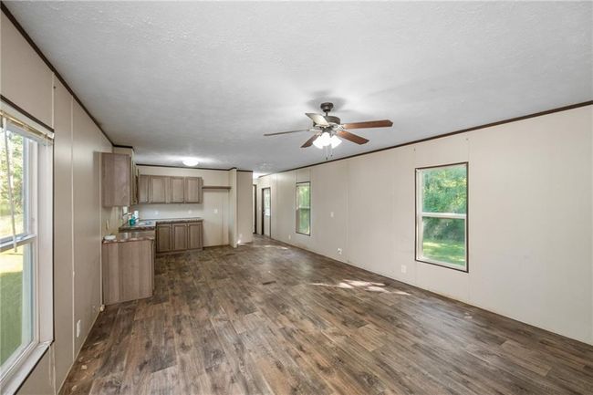 Unfurnished living room with dark wood-type flooring, a ceiling fan, and plenty of natural light | Image 9