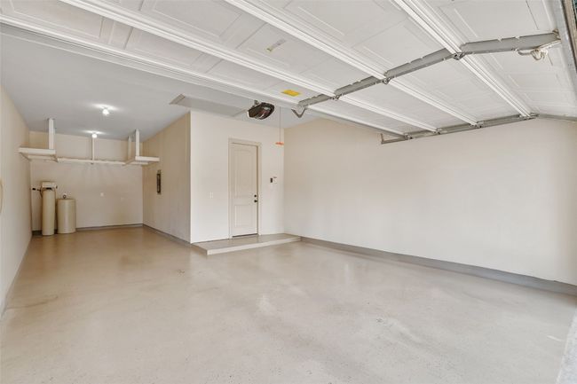 Garage featuring a garage door opener and baseboards | Image 35