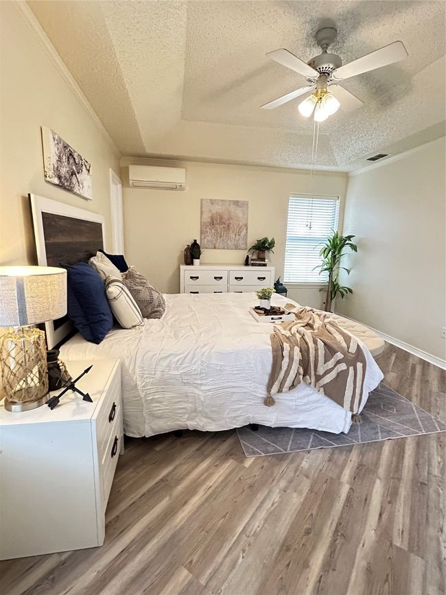 Bedroom with ornamental molding, a textured ceiling, a wall mounted AC, and dark wood-style flooring | Image 35