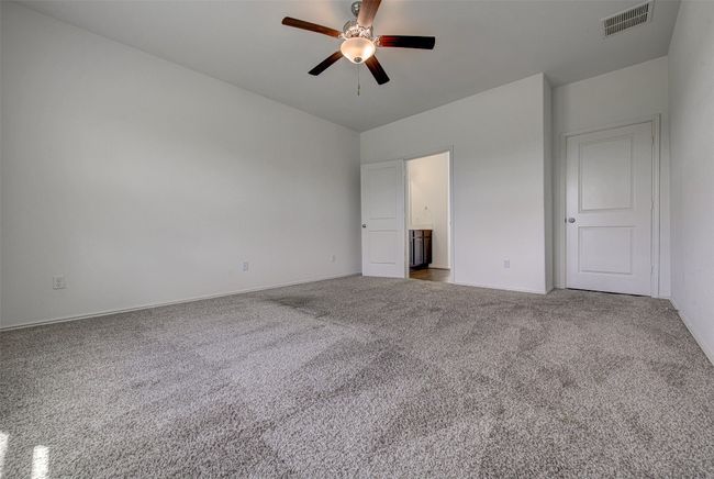 Unfurnished bedroom featuring carpet floors, baseboards, connected bathroom, and ceiling fan | Image 15