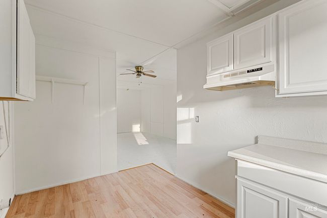 Kitchen with under cabinet range hood, light countertops, light wood-style floors, and ceiling fan | Image 23
