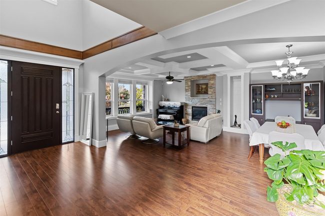 Foyer entrance with a stone fireplace, a ceiling fan, wood-type flooring, a chandelier, and arched walkways | Image 4