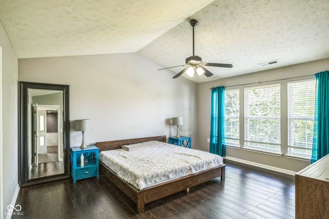 bedroom with a textured ceiling, wood finished floors, vaulted ceiling, and ceiling fan | Image 23