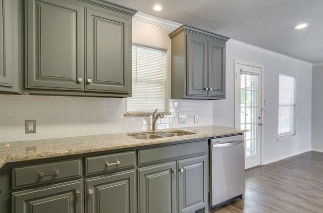 Kitchen with dishwasher, crown molding, decorative backsplash, dark wood-style floors, and light stone counters | Image 15