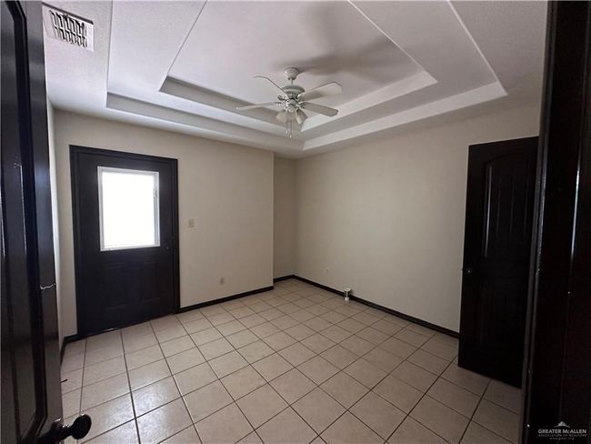 Tiled spare room with a raised ceiling and ceiling fan | Image 4