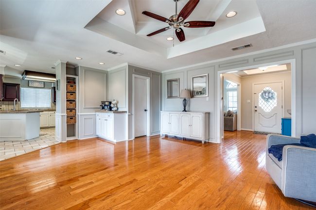 Living area with a ceiling fan, healthy amount of natural light, light wood-style floors, and crown molding | Image 8