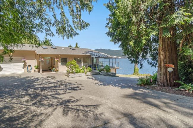 Ranch-style house with a water view, an attached garage, stucco siding, and driveway | Image 79