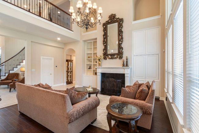 Living area with a high ceiling, healthy amount of natural light, built in features, dark wood-style flooring, and a tiled fireplace | Image 14