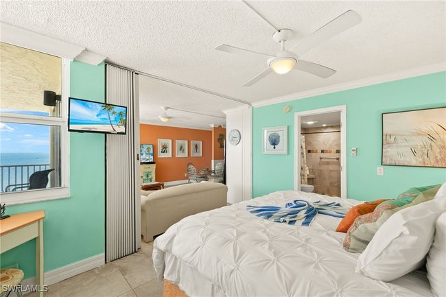 Bedroom featuring a textured ceiling, ornamental molding, ceiling fan, ensuite bath, and light tile patterned flooring | Image 15