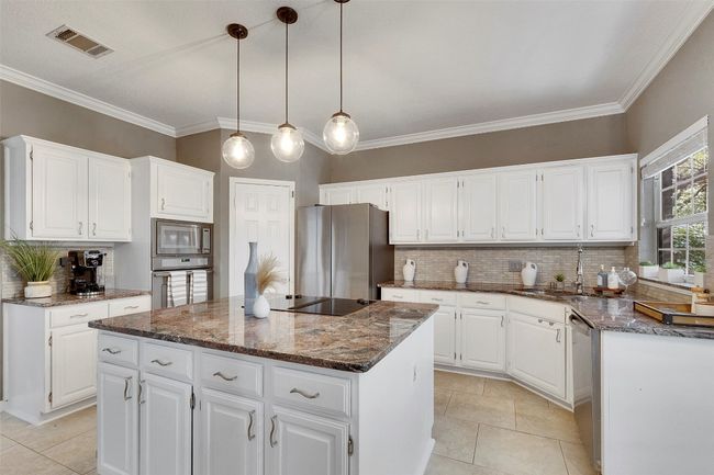 Kitchen with appliances with stainless steel finishes, a kitchen island, backsplash, dark stone counters, and light tile patterned floors | Image 7
