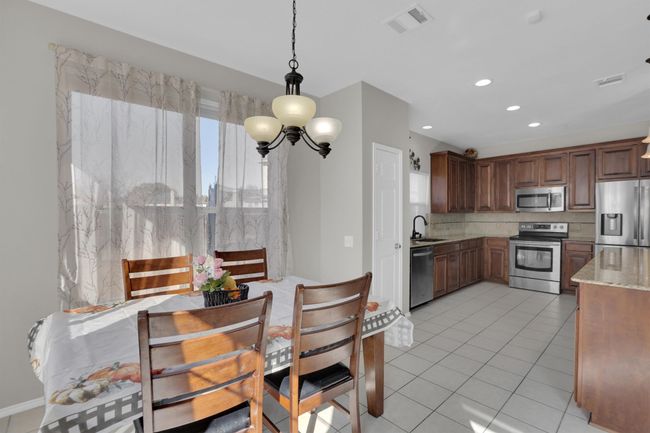 Kitchen with visible vents, decorative backsplash, appliances with stainless steel finishes, decorative light fixtures, and light stone countertops | Image 11