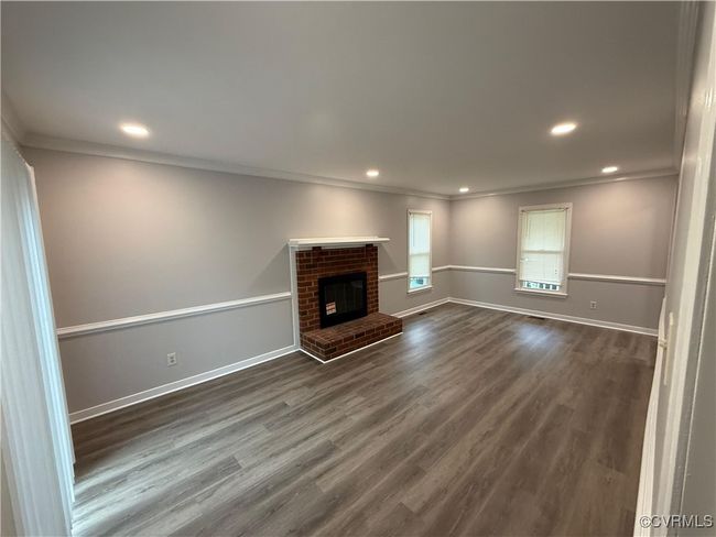 Unfurnished living room featuring ornamental molding, dark wood-type flooring, baseboards, recessed lighting, and a fireplace | Image 8