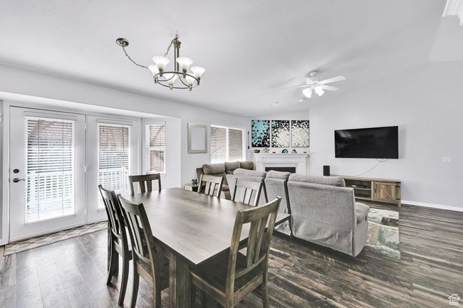 Dining area featuring baseboards, a fireplace, dark wood finished floors, ceiling fan with notable chandelier, and vaulted ceiling | Image 12