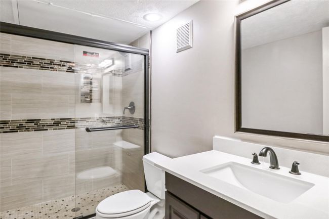 Full bathroom featuring a shower stall, toilet, vanity, and a textured ceiling | Image 5