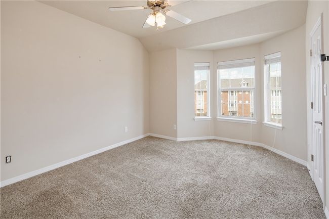 Empty room with light carpet, a ceiling fan, and baseboards | Image 10