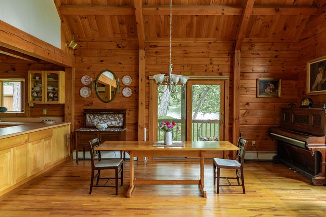 Dining area with wooden ceiling with exposed beams, wooden walls, plenty of natural light, light wood-style flooring, and a chandelier | Image 4